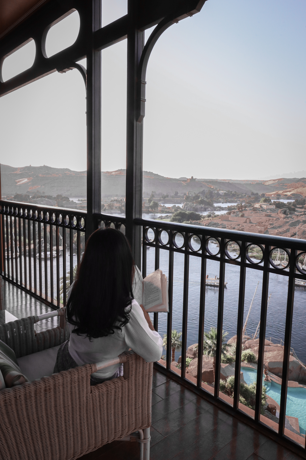 Jordan Gassner reading Agatha Christie's Death on the Nile on one of the guest room balconies overlooking the Nile River at the Sofitel Old Cataract Hotel in Aswan, Egypt