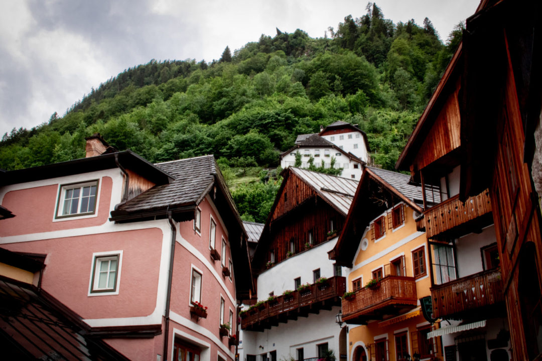 Low angle view of the traditional pink, yellow and wooden buildings that sit beneath one of the many mountains surrounding Hallstatt town