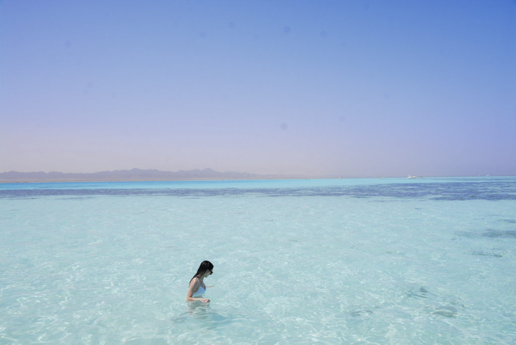 Solo Female Traveler wearing a white bikini in the turquoise waters at the Red Sea, Egypt