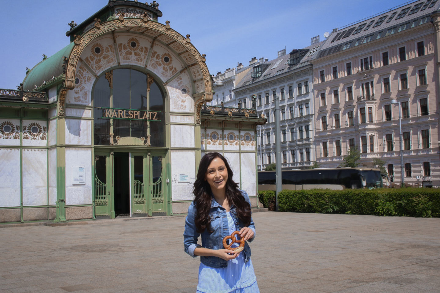 Jordan Gassner holding a pretzel in front of the old and art nouveau Karlsplatz station in Vienna, Austria