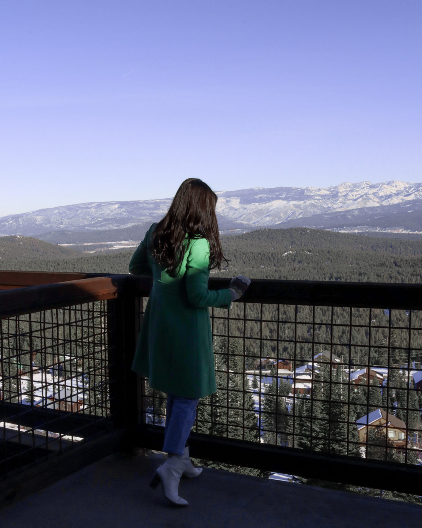 Travel Blogger Jordan Gassner peering over the railing of a balcony in snowy Truckee, California