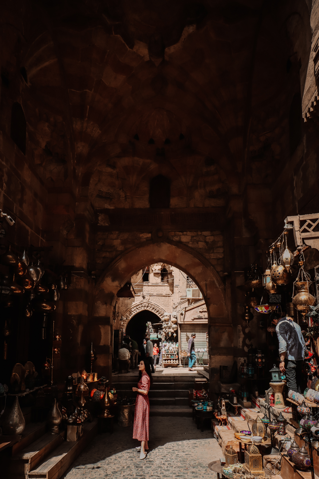 Solo female traveler wearing a burgundy vintage-inspired midi dress in the Khan el-Khalili Bazaar in Cairo, Egypt
