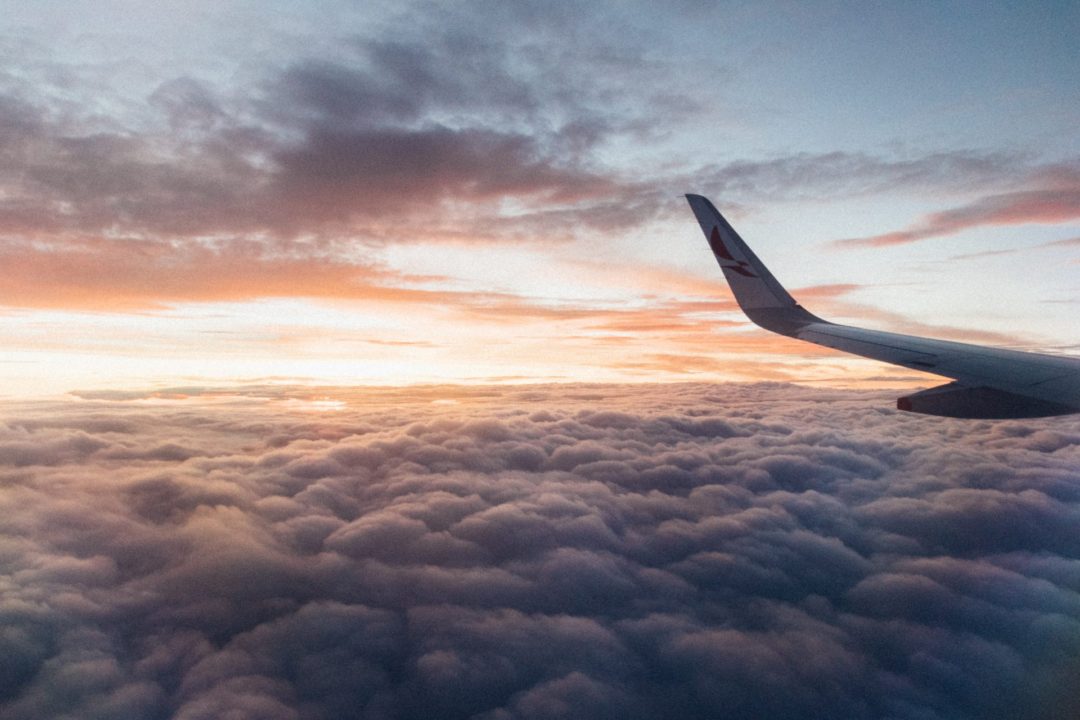 A sea of clouds as seen from the window of an airplane around sunset