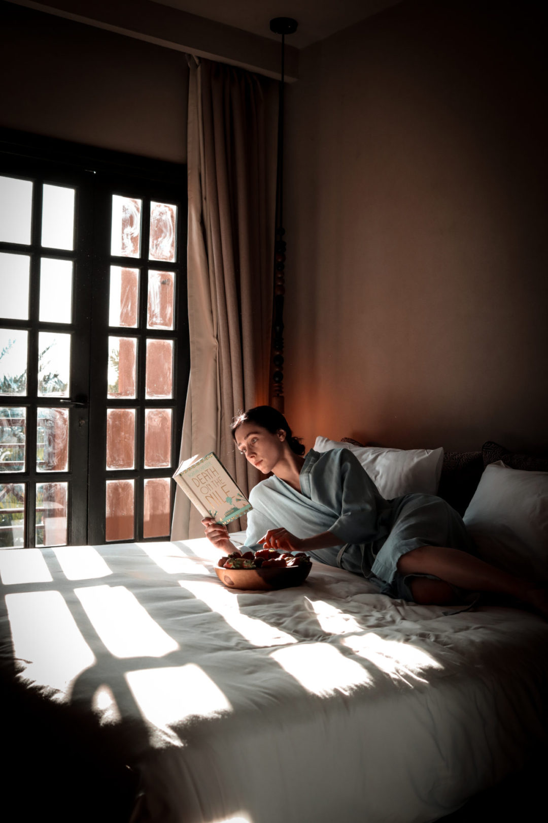 Travel Blogger Jordan Gassner eating fruit and reading Death on the Nile by Agatha Christie inside a hotel room in El Gouna, Egypt
