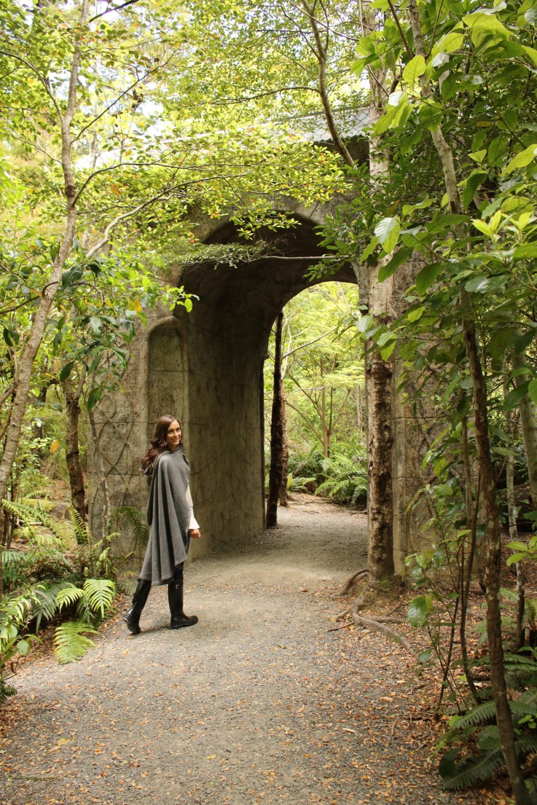 Visiting New Zealand: Travel Blogger, Jordan Gassner, wearing a cape and walking through the Rivendell archway at Kaitoke Regional Park in New Zealand