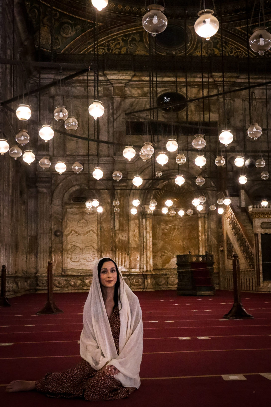 Jordan Gassner sitting without shoes and wearing a scarf over her head inside one of the must-see Cairo mosques - the Alabaster Mosque 