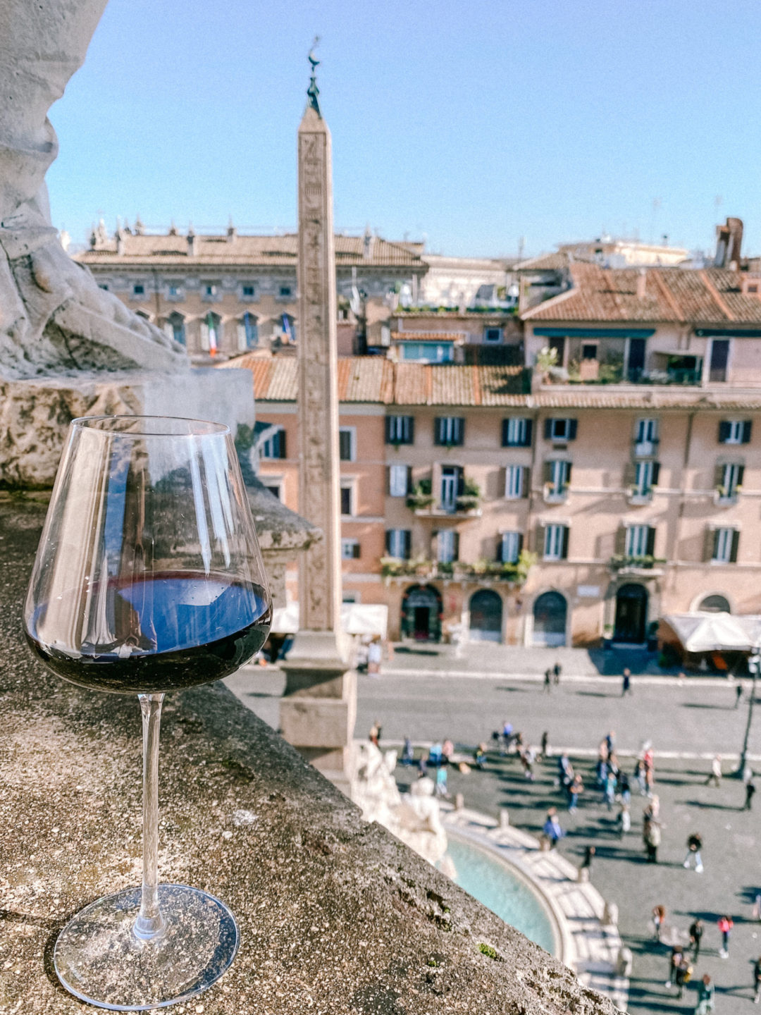 A glass of red wine on a balcony overlooking Piazza Navona in Rome, Italy
