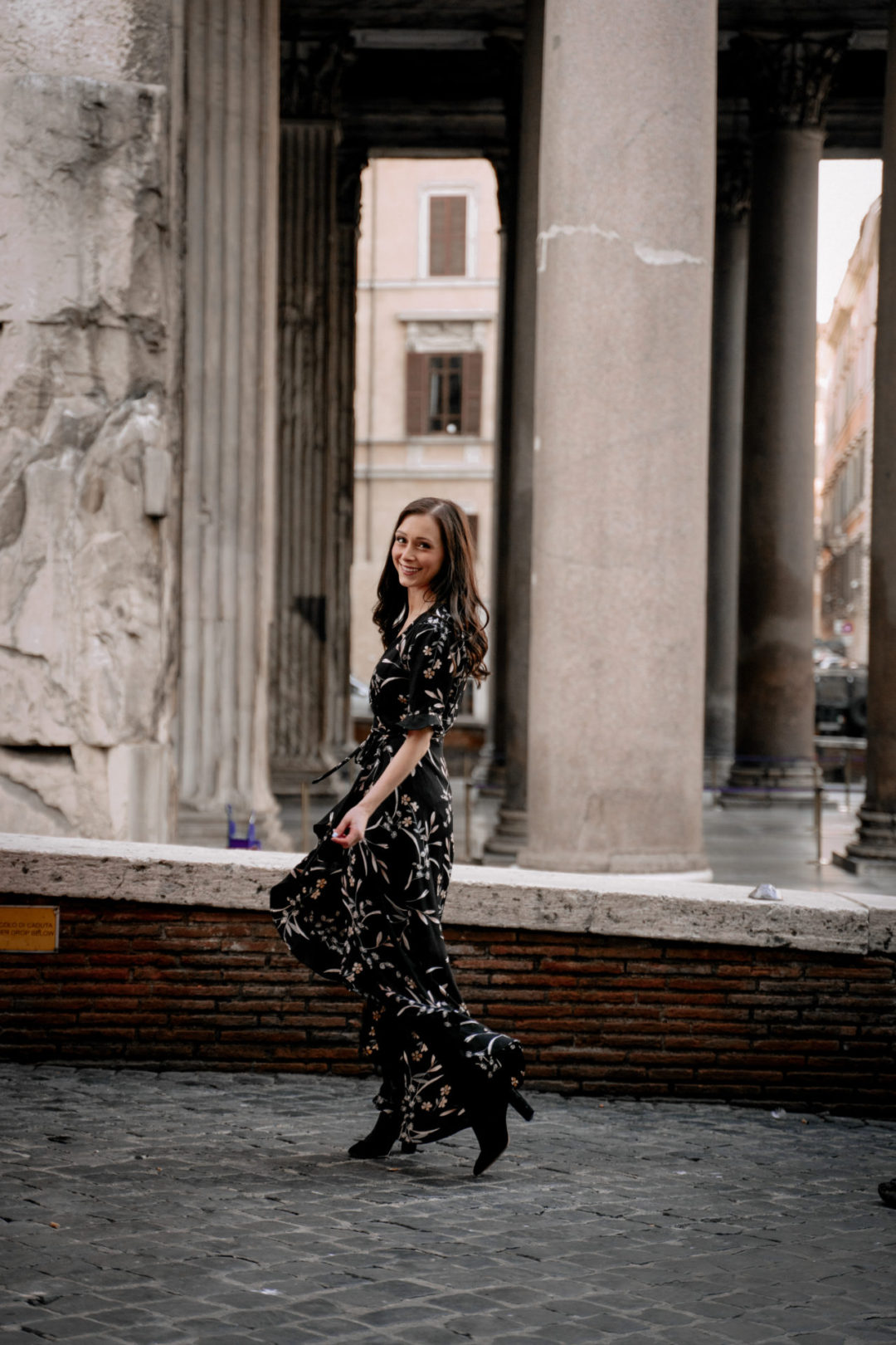 Jordan Gassner twirling in a black floral dress alongside the Pantheon in Rome, Italy