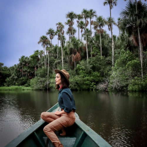 Jordan Gassner wearing an explorer outfit while canoeing through Lake Sandoval, Tambopata National Reserve in Puerto Maldonado, Peru, The Amazon