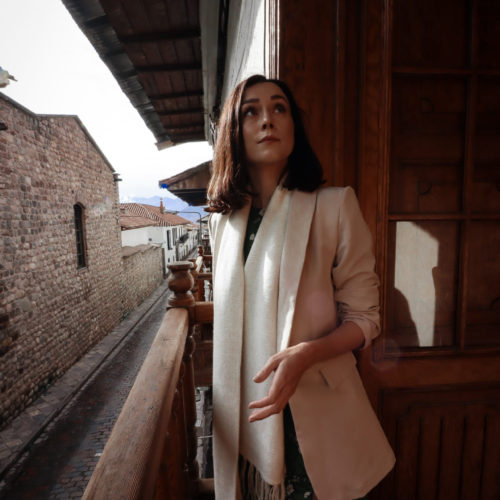 Jordan Gassner looking up and out on an old wooden balcony at Casa Biru Hotel in Cusco, Peru