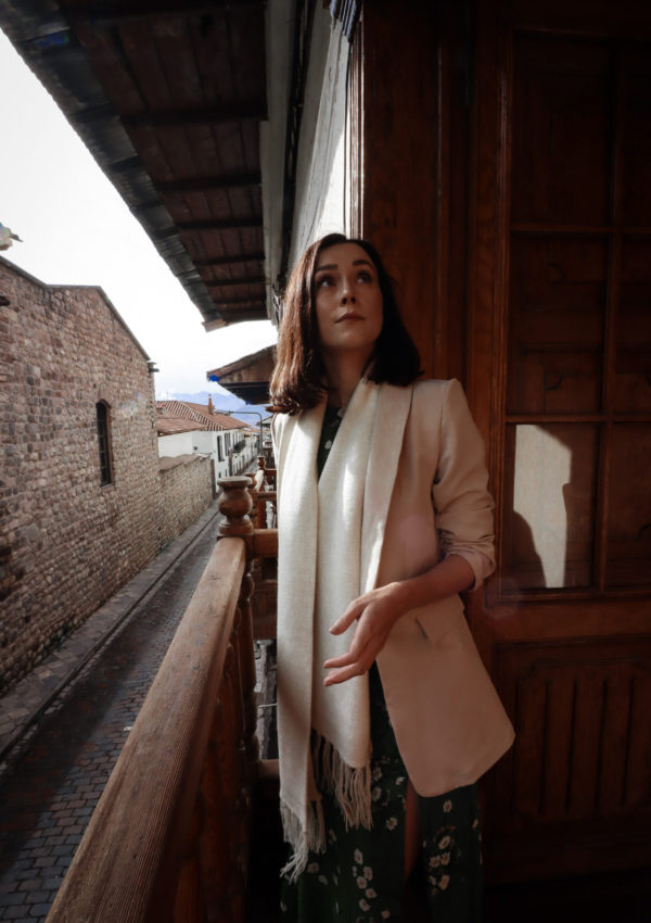 Jordan Gassner looking up and out on an old wooden balcony at Casa Biru Hotel in Cusco, Peru