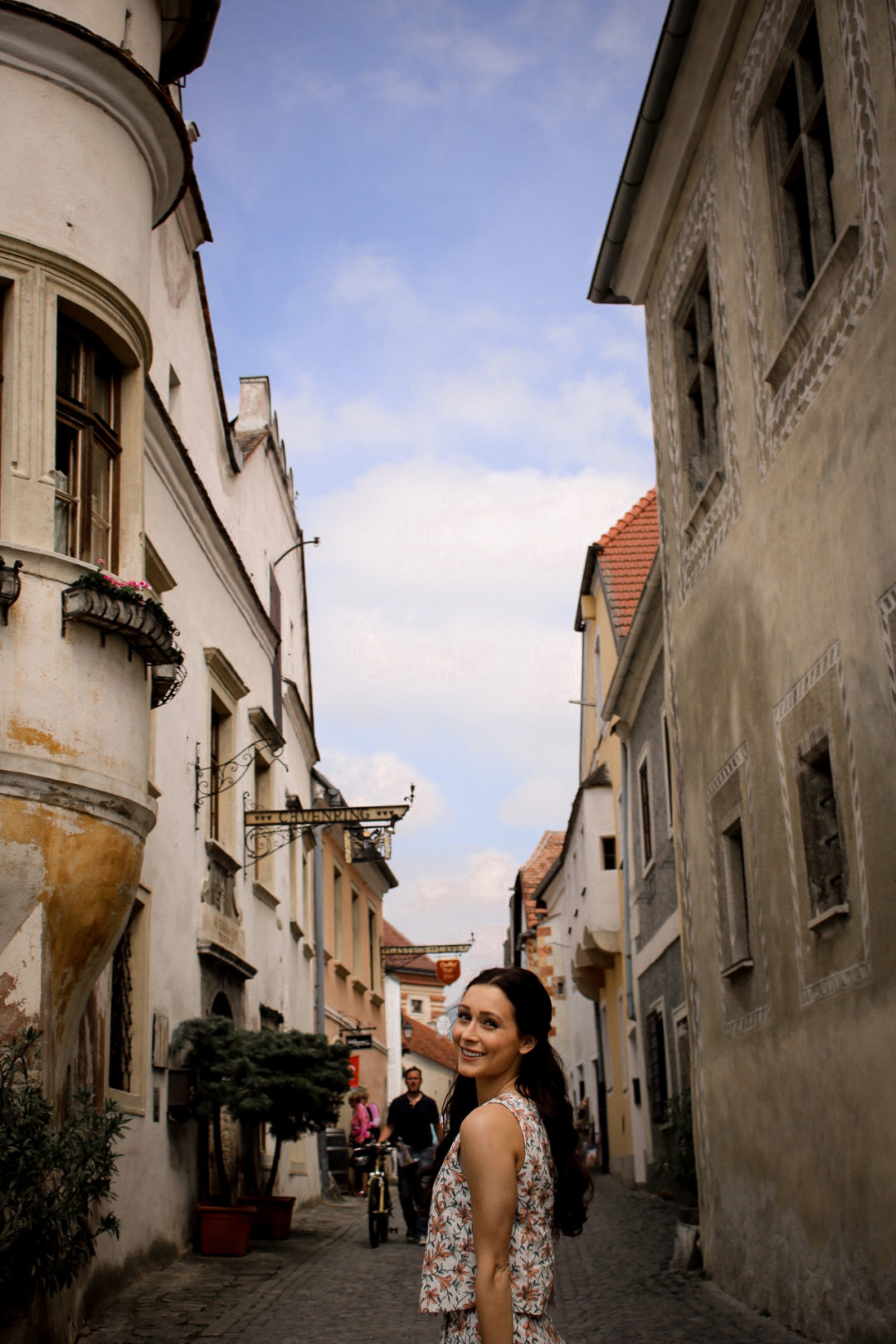 Travel Blogger Jordan Gassner smiling along the main cobblestone street of Durnstein, just a short day trip away from Vienna, Austria