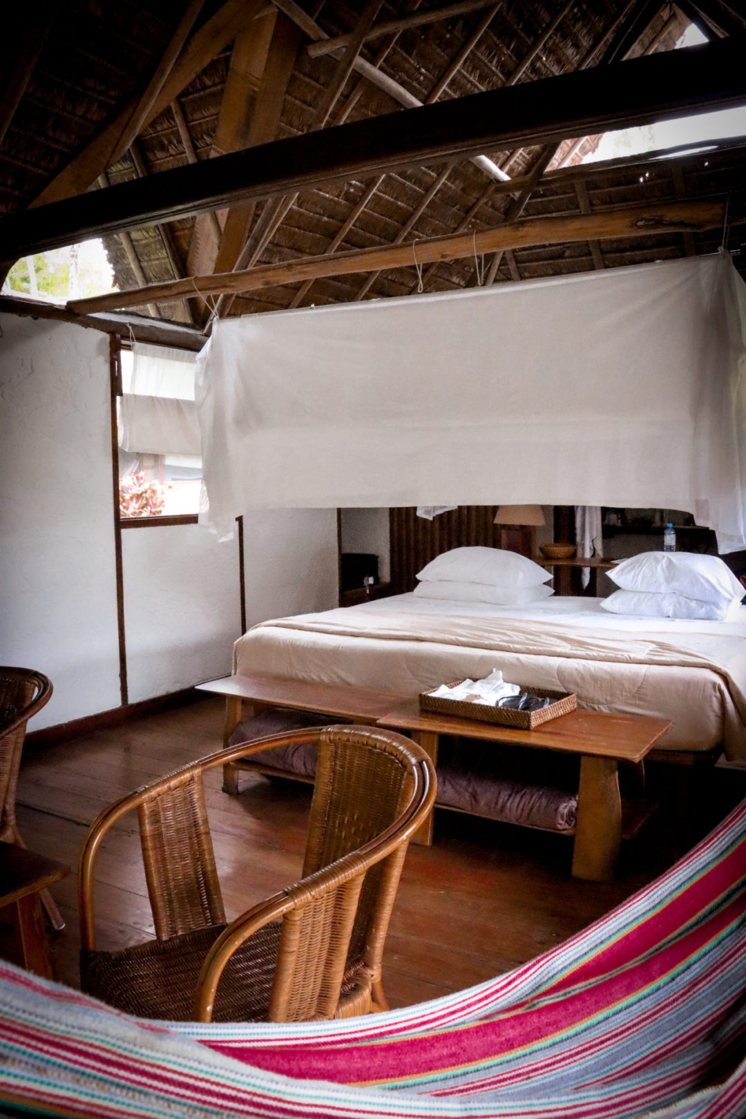 Bed and Canopy inside a Wooden Thatched-Roof Bungalow at Inkaterra Reserva Amazonica