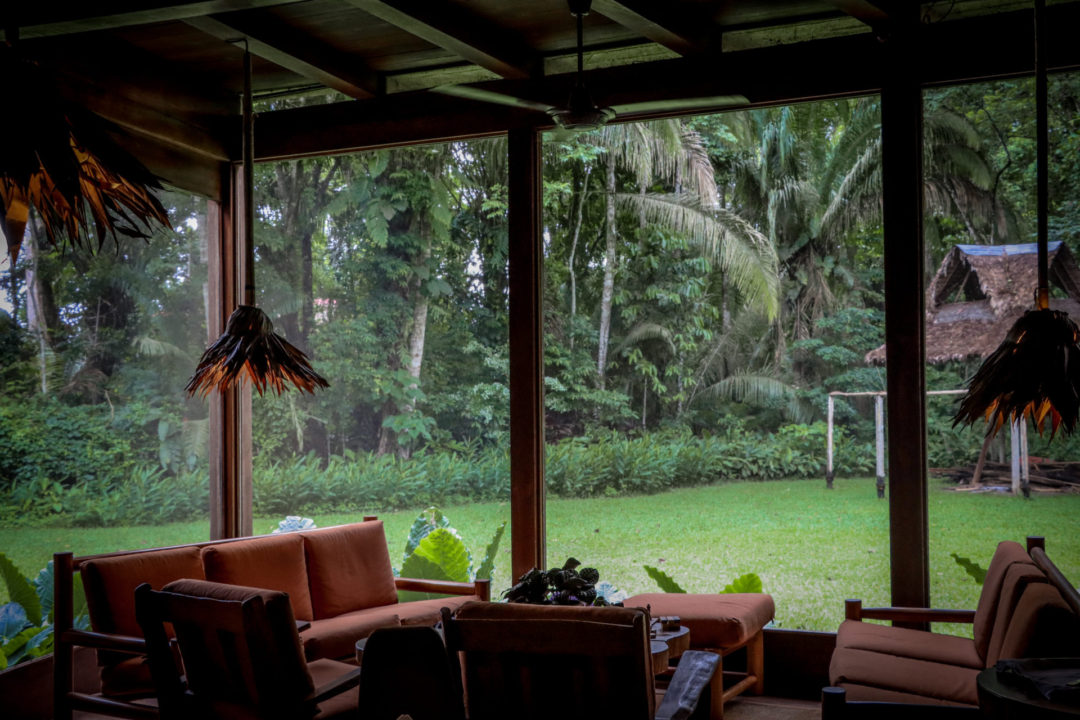 Sitting area with two orange cushioned chairs and two orange sofas surrounding a wooden table inside of Inkaterra Reserva Amazonica at Puerto Maldonado, Peru, The Amazon