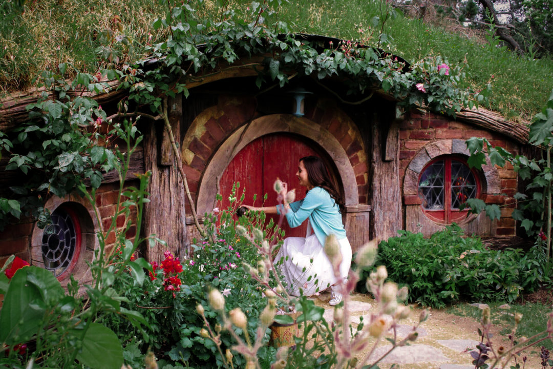 Visit New Zealand: Travel Blogger, Jordan Gassner kneeling down while attempting to enter a Hobbit House in New Zealand