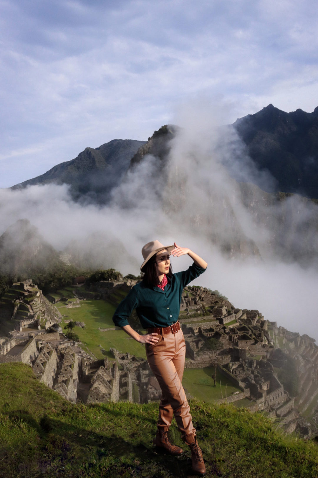 Travel Blogger Jordan Gassner shielding her eyes at the top of the lower terrace in Machu Picchu, Peru