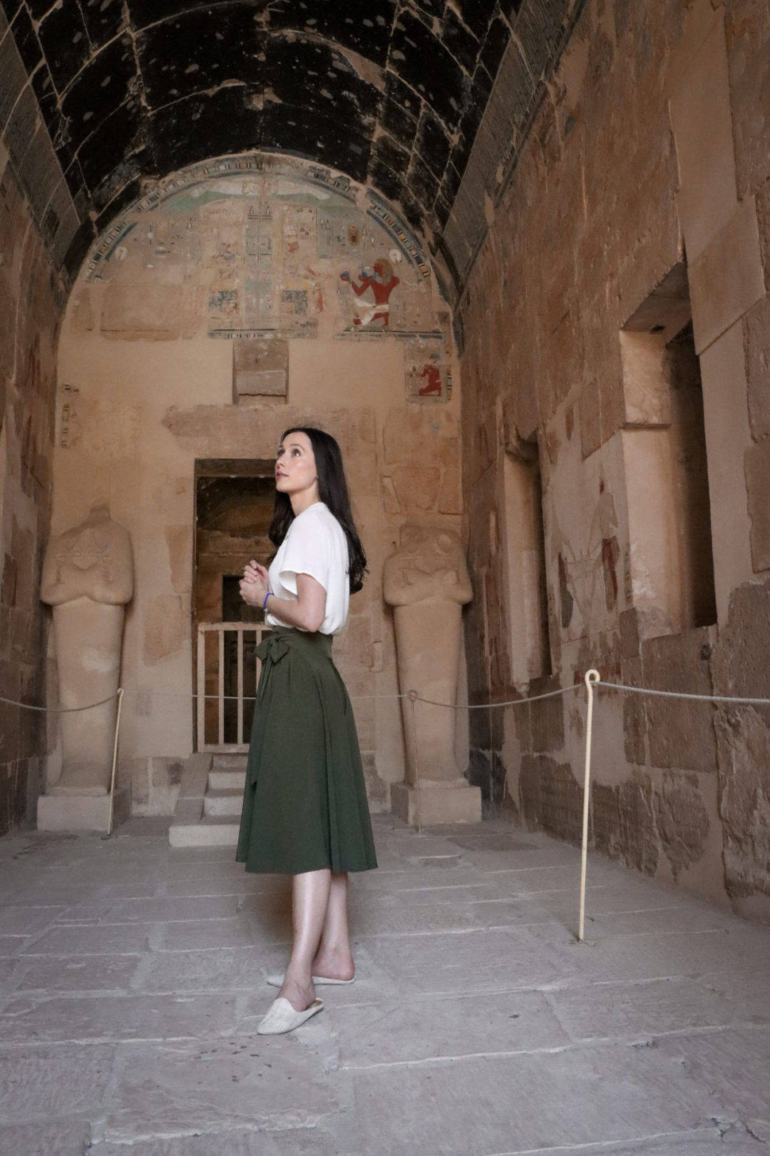 Travel Blogger Jordan Gassner wearing a white button down shirt and army green midi skirt inside the Ancient Egyptian Mortuary Temple of Hatshepsut