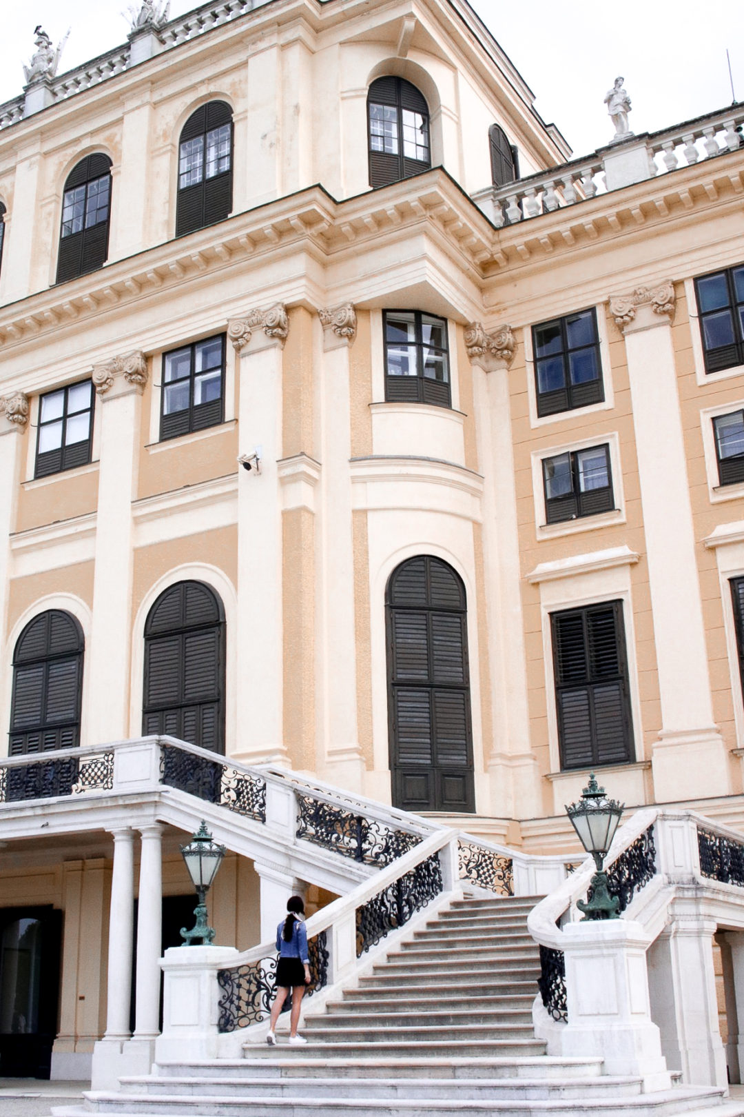 Vienna Travel Guide Travel Blogger Jordan Gassner walking up stairs leading to the imposing Schönbrunn Palace