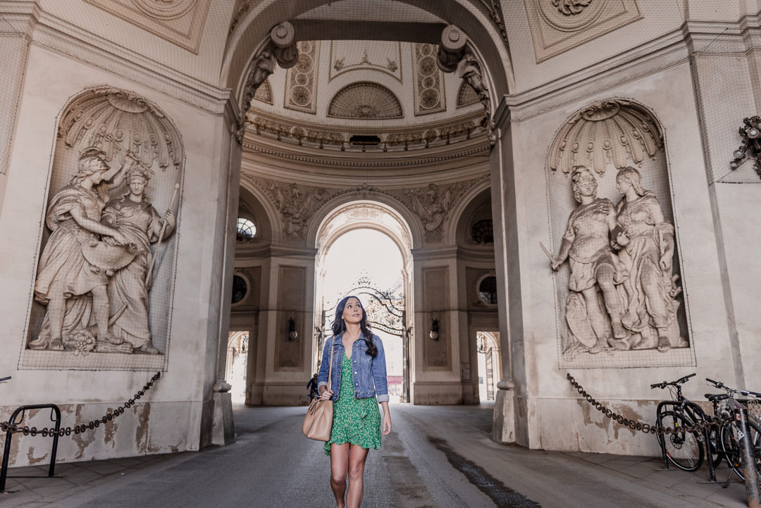 Vienna Travel Guide: Travel Blogger Jordan Gassner walking under the domed entrance of Hofburg Palace in the Innere Stadt neighborhood