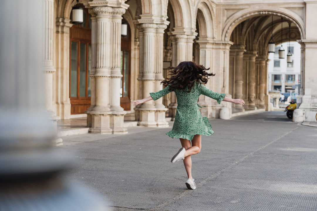 Vienna Travel Guide: Travel Blogger Jordan Gassner twirls under the outdoor colonnade at the Vienna State Opera House