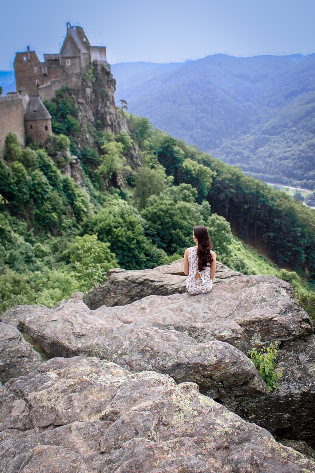 Travel Blogger Jordan Gassner gazing out at Aggstein Castle from a rocky hilltop in Austria's Wachau Valley
