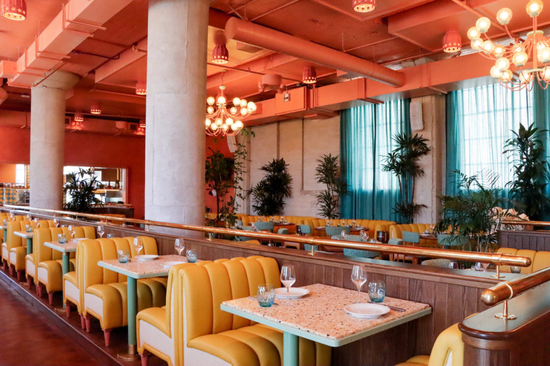 The yellow, coral and turquoise interior of the Mother Tongue Restaurant inside HEIMAT in Los Angeles, California