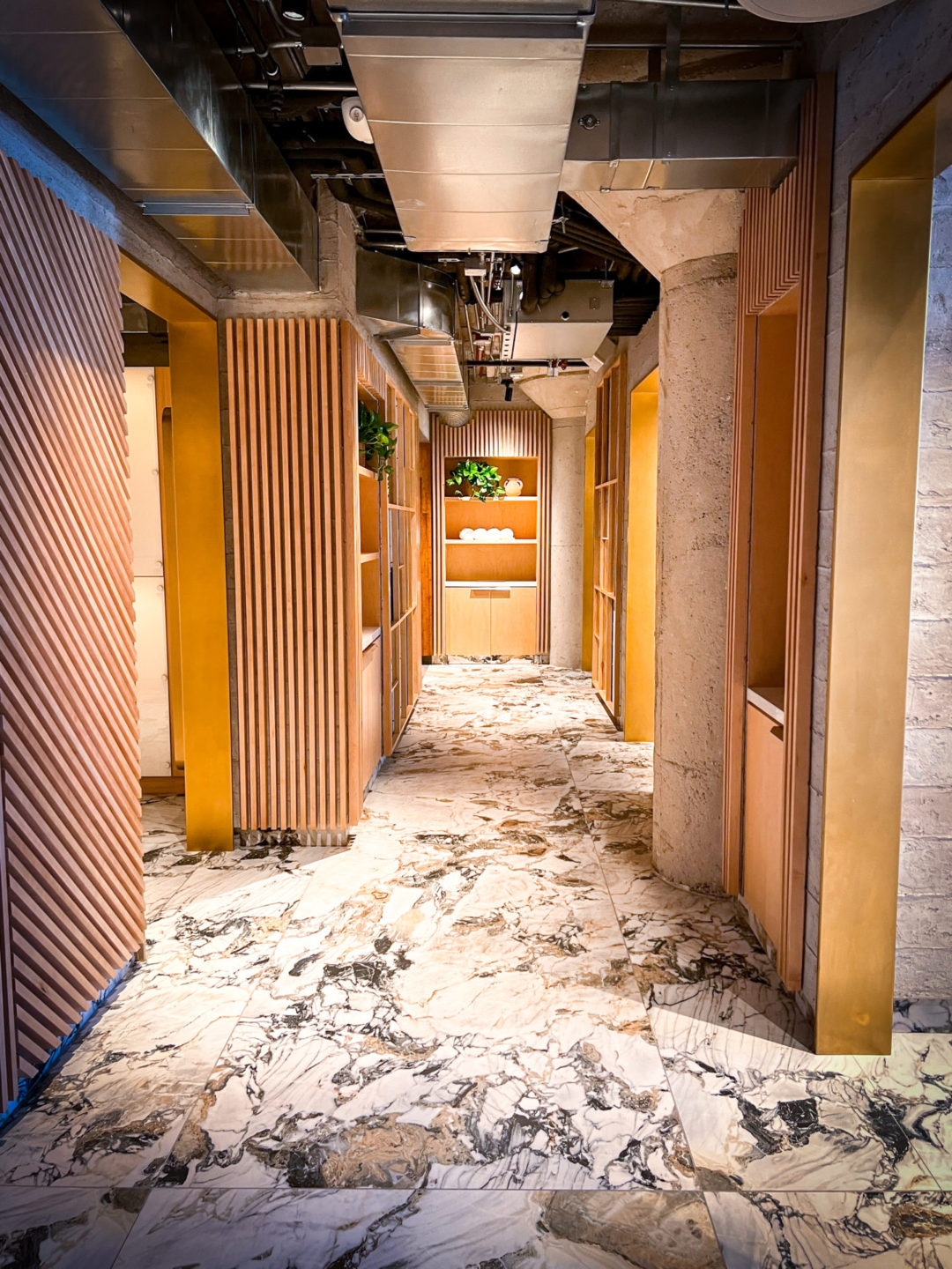 Marble floors and modern wood panelling inside the empty main hallway inside the women's locker room of Heimat Club in Los Angeles, California