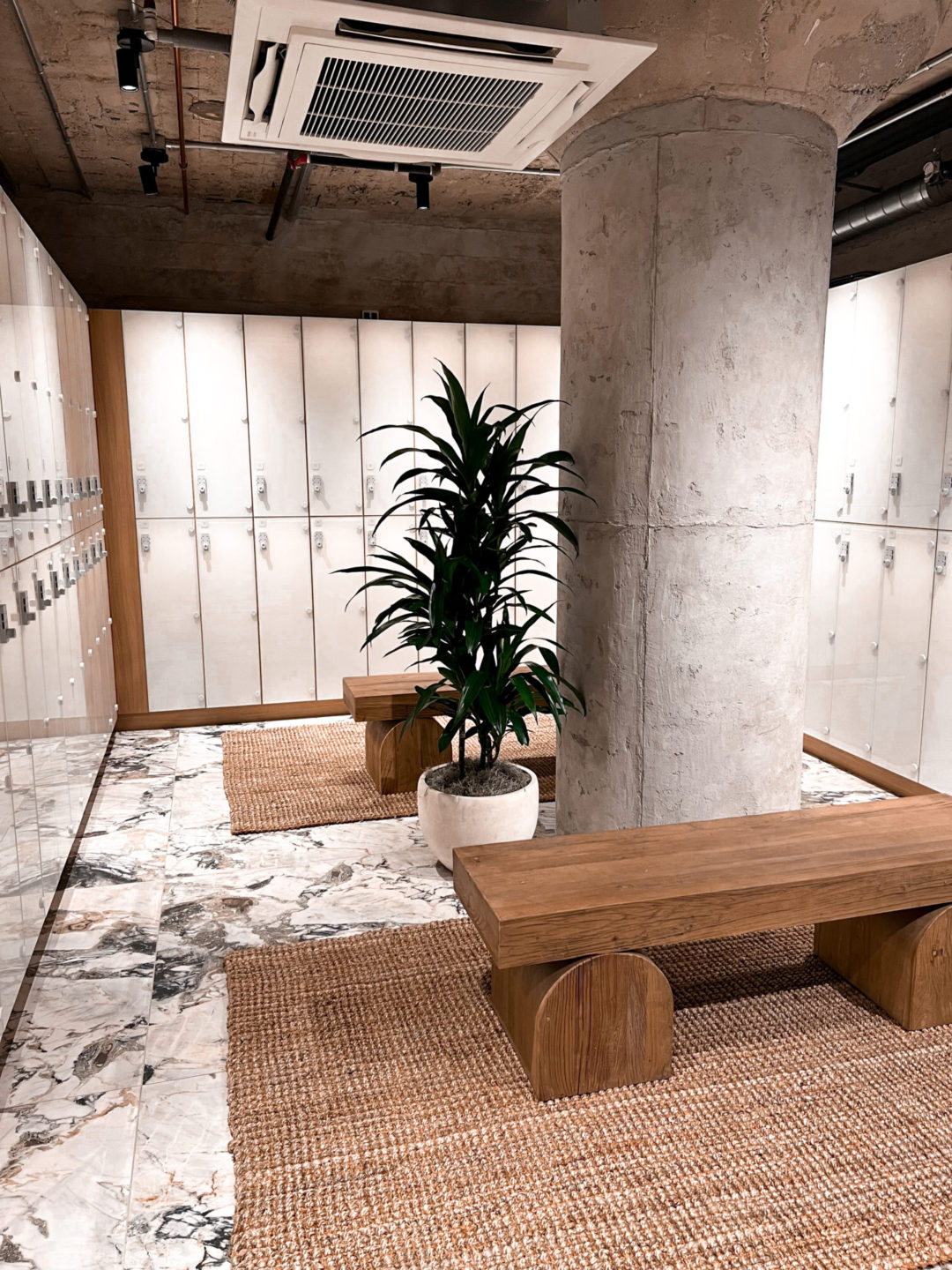 An empty locker with marble floors, modern, wood benches and rattan rugs inside Heimat Club in Los Angeles, California