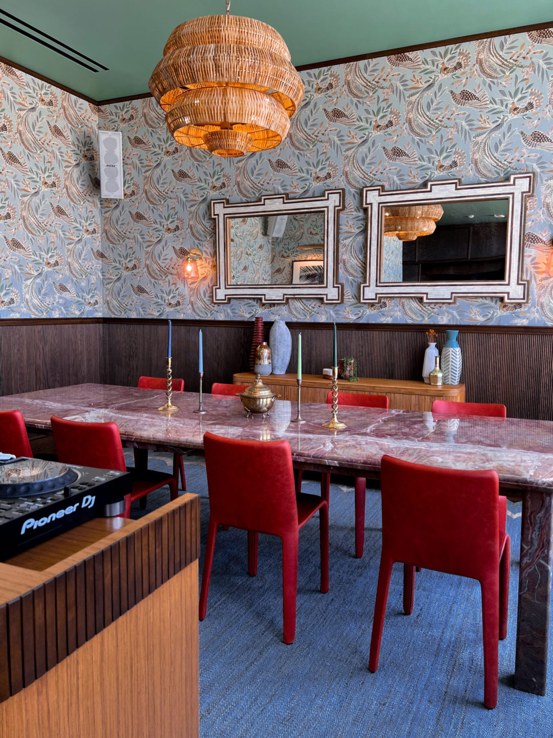 Heimat Review: A marble dining table. with red velvet chairs inside a hotel 70s-inspired wallpaper designed room in Heimat LA's coworking space