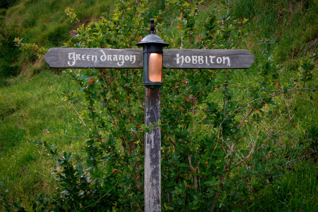 A directional sign reading "Green Dragon" on one side and "Hobbiton" on the other side in Hobbiton New Zealand