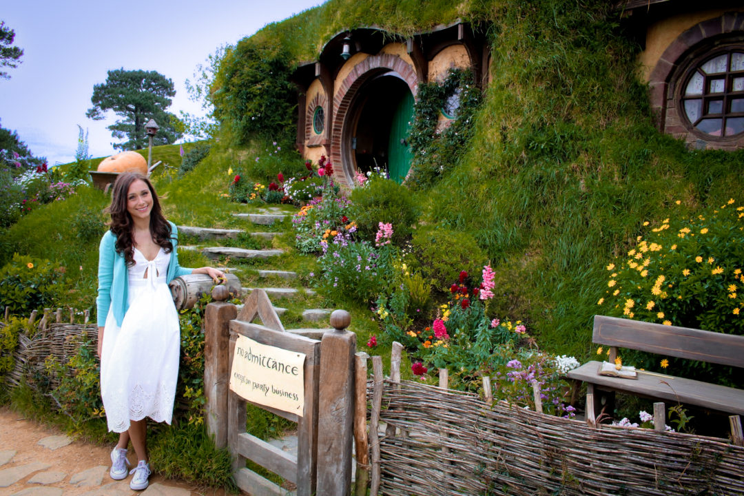 Travel Blogger Jordan Gassner standing in front of the "No Admittance Except on Party Business" sign at Bag End in Hobbiton New Zealand