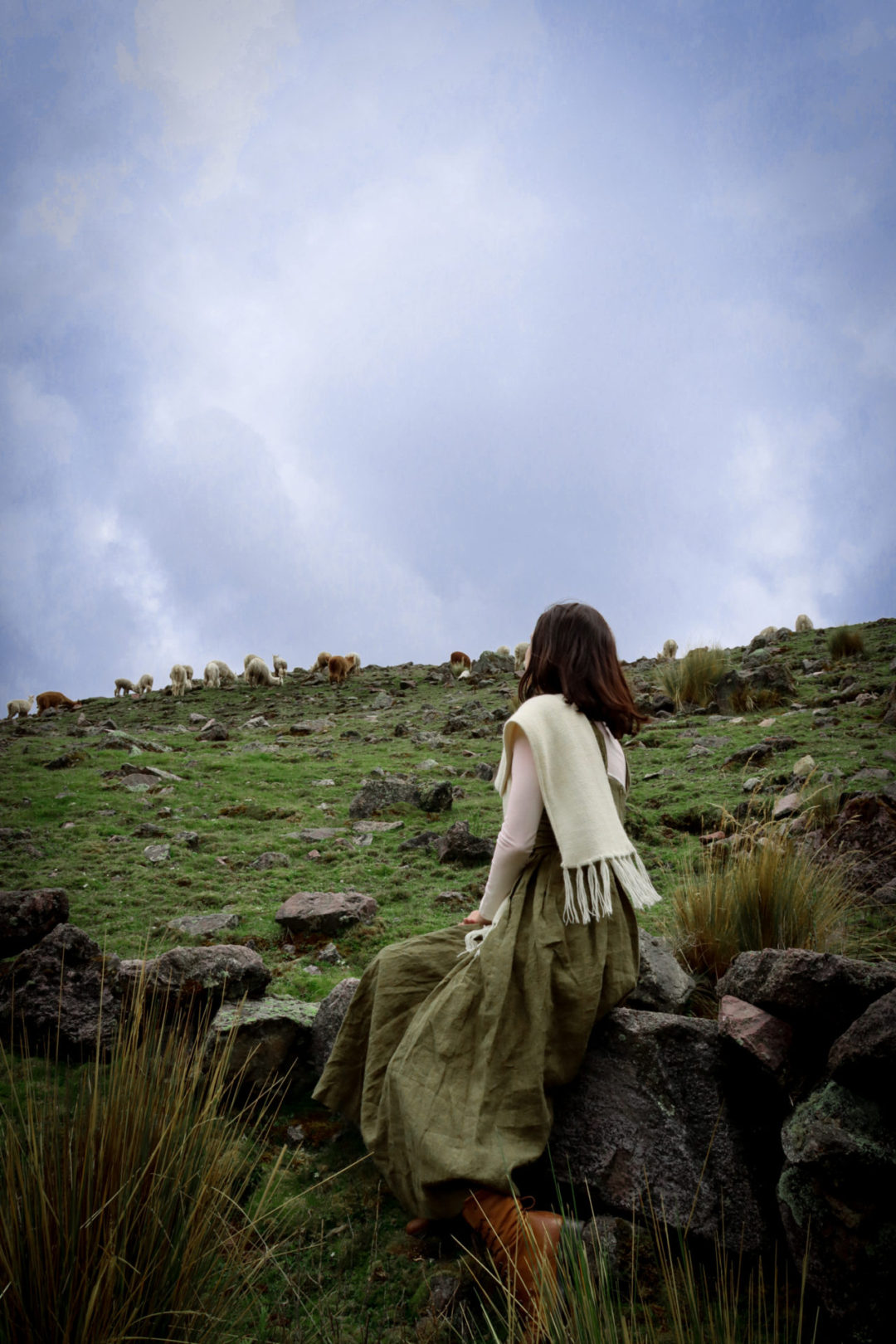 Travel Blogger Jordan Gassner sitting near a pack of alpacas on Ausangate Trek near Cusco, Peru