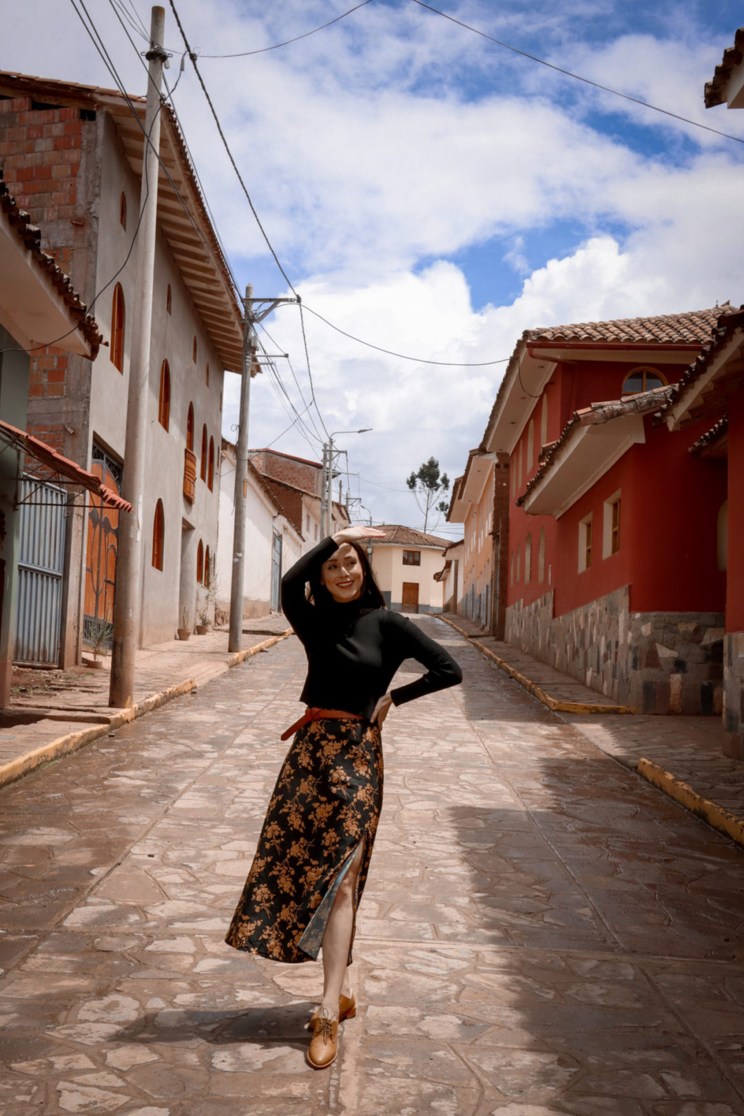 Travel Blogger Jordan Gassner shielding her eyes from the sun along a colorful street in Chichero, Peru
