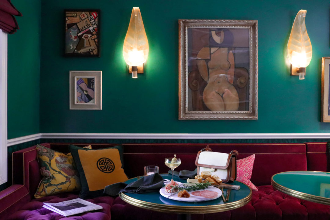 Two drinks and light appetizers on top of a green table in the Hollywood Regency decorated lobby of The Prospect Hollywood in California