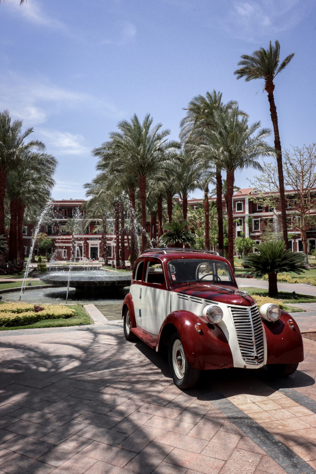 A vintage red and white car in front of the Sofitel Legend Old Cataract Hotel in Aswan, Egypt