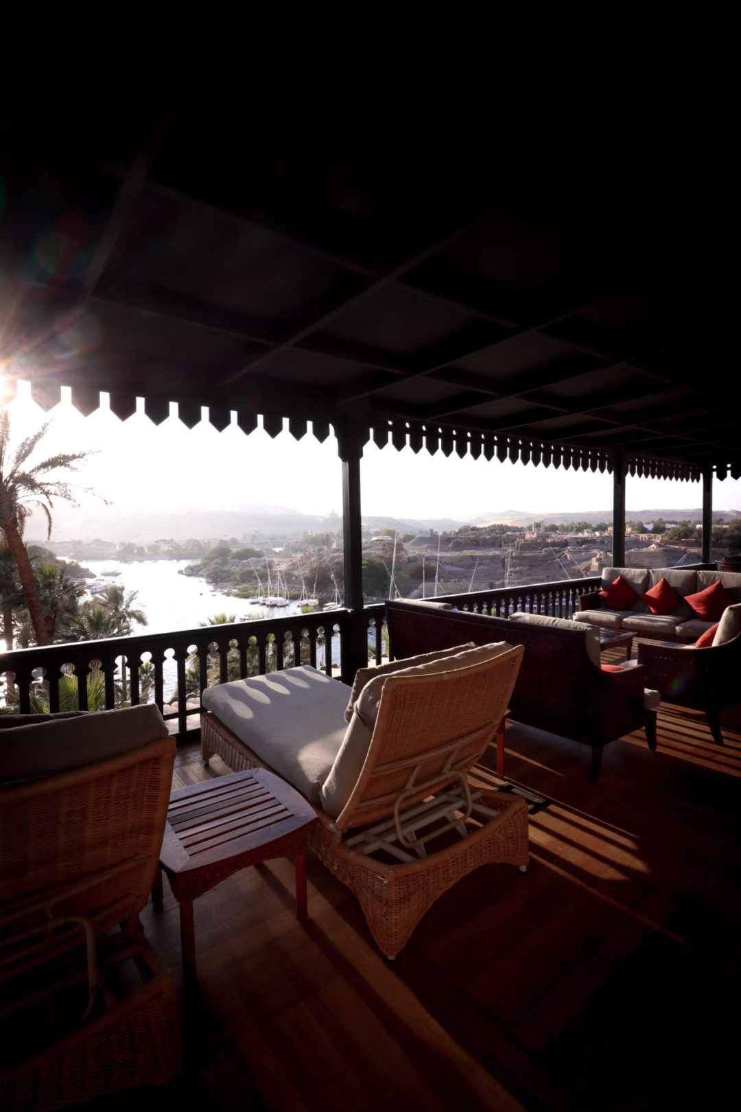A straw lounge chair and set of sofas overlooking the Nile River from the top of a balcony at the Sofitel Old Cataract Hotel in Aswan, Egypt