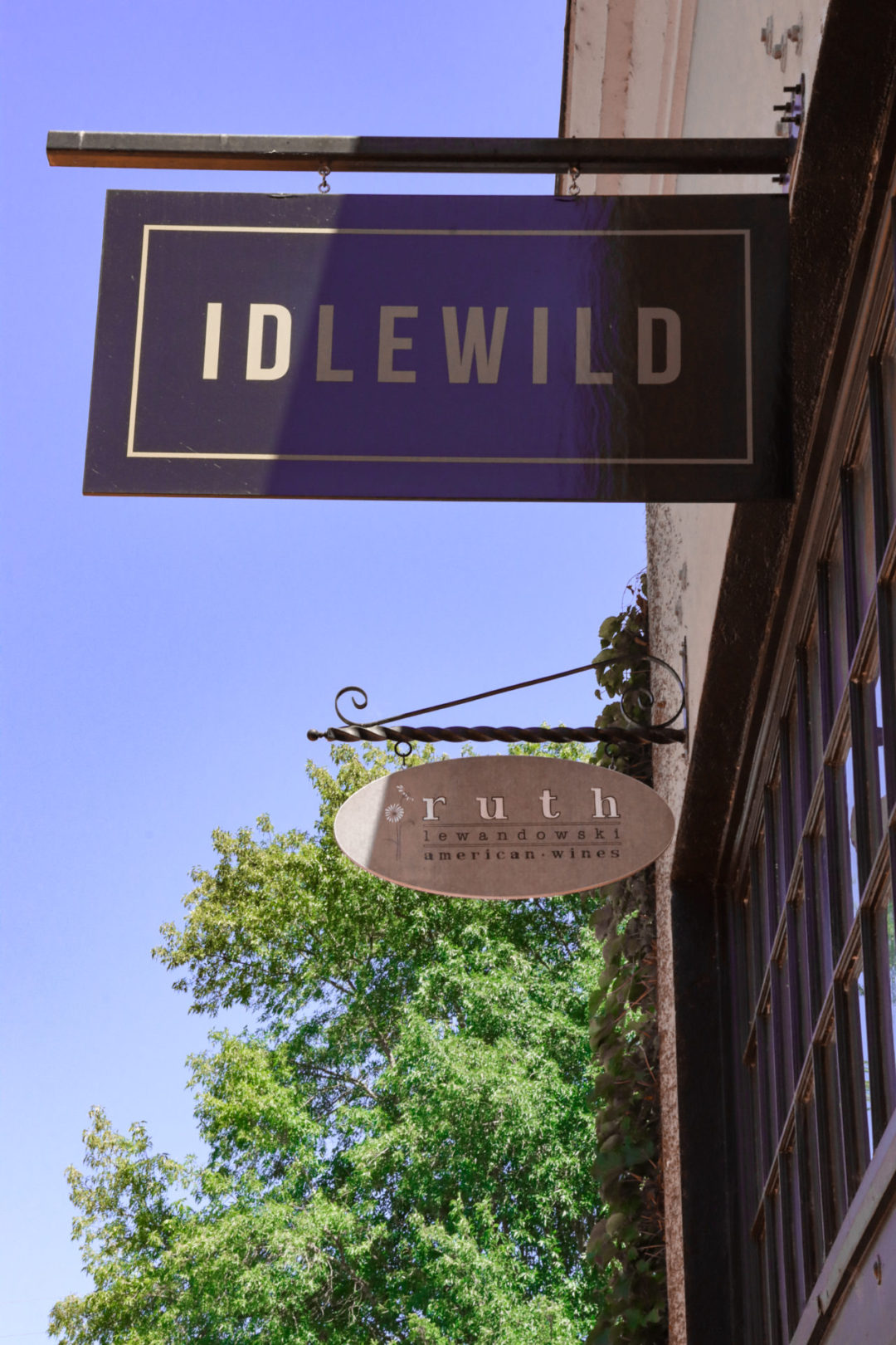 Healdsburg Travel Guide: Two signs "Idlewild" and "Ruth Lewandowski Wines" hanging from a brick storefront