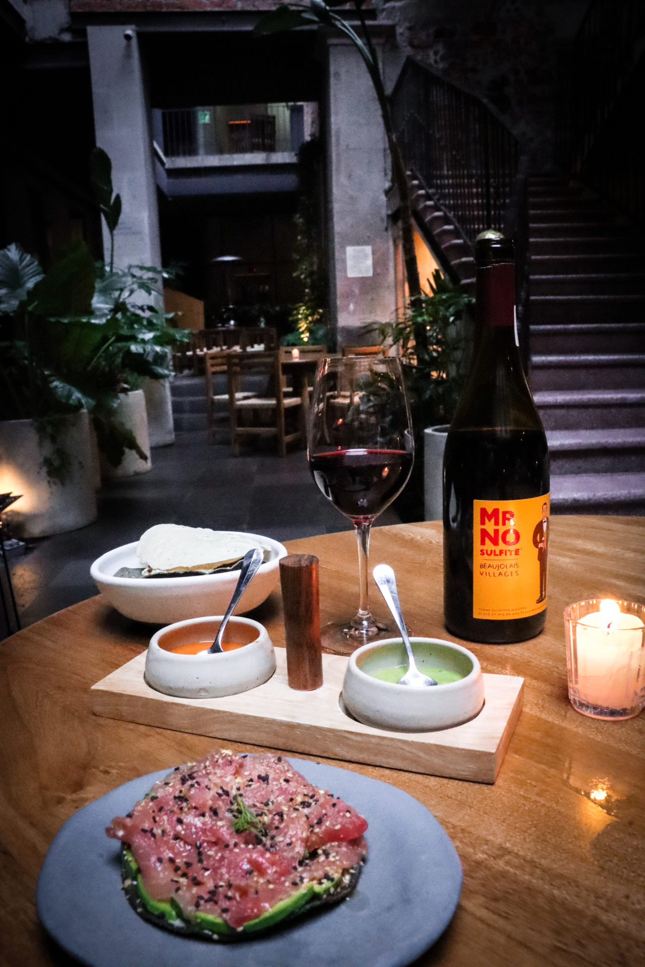 Tuna Tostada, Fried Tortillas with dip and a glass of red wine near a bottle of Mr. No Sulfite Beaujolais-Villages on a table at Caracol de Mar in CDMX