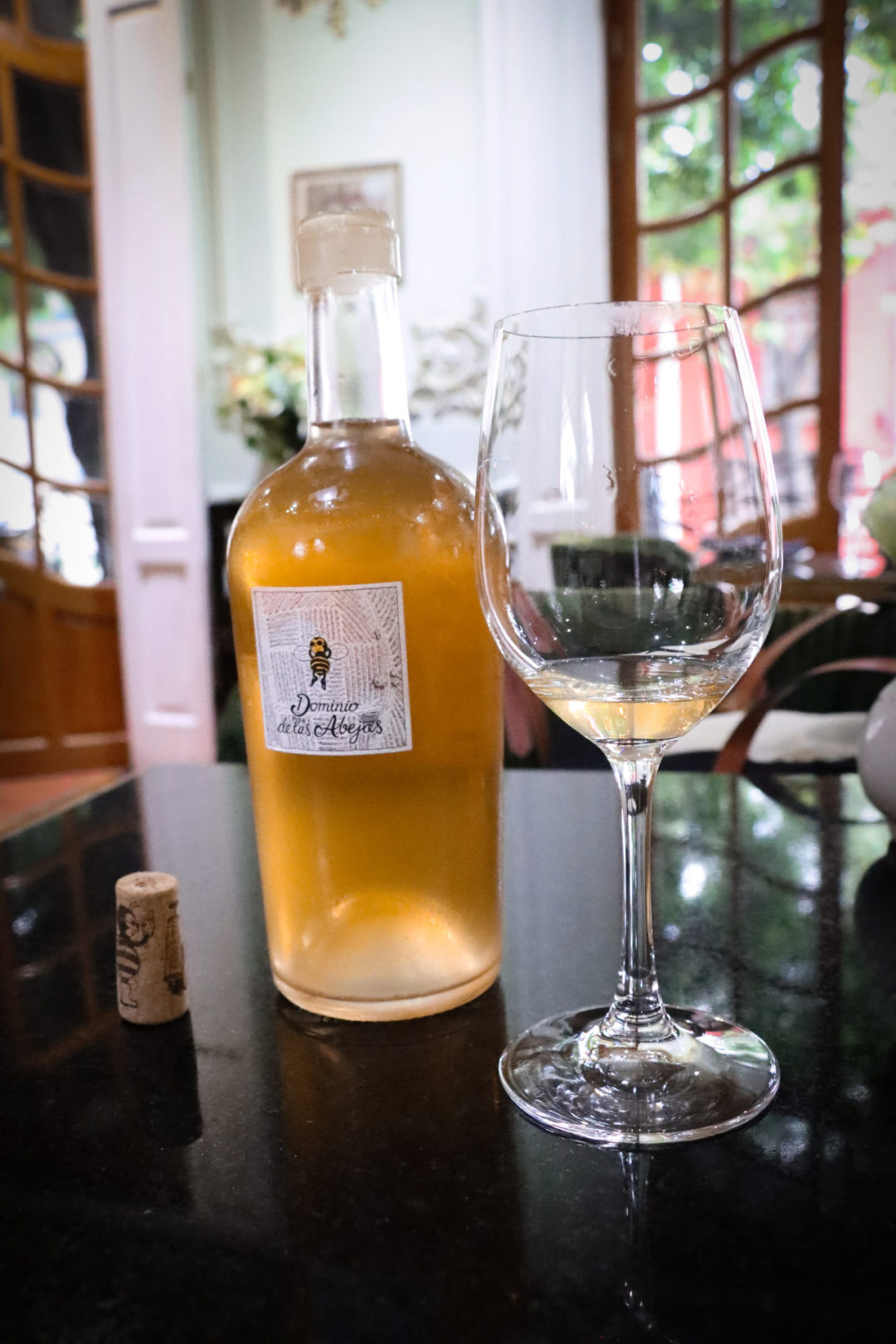A glass of wine next to a bottle of the natural Domino de las Abejas orange wine at Galanga Thai