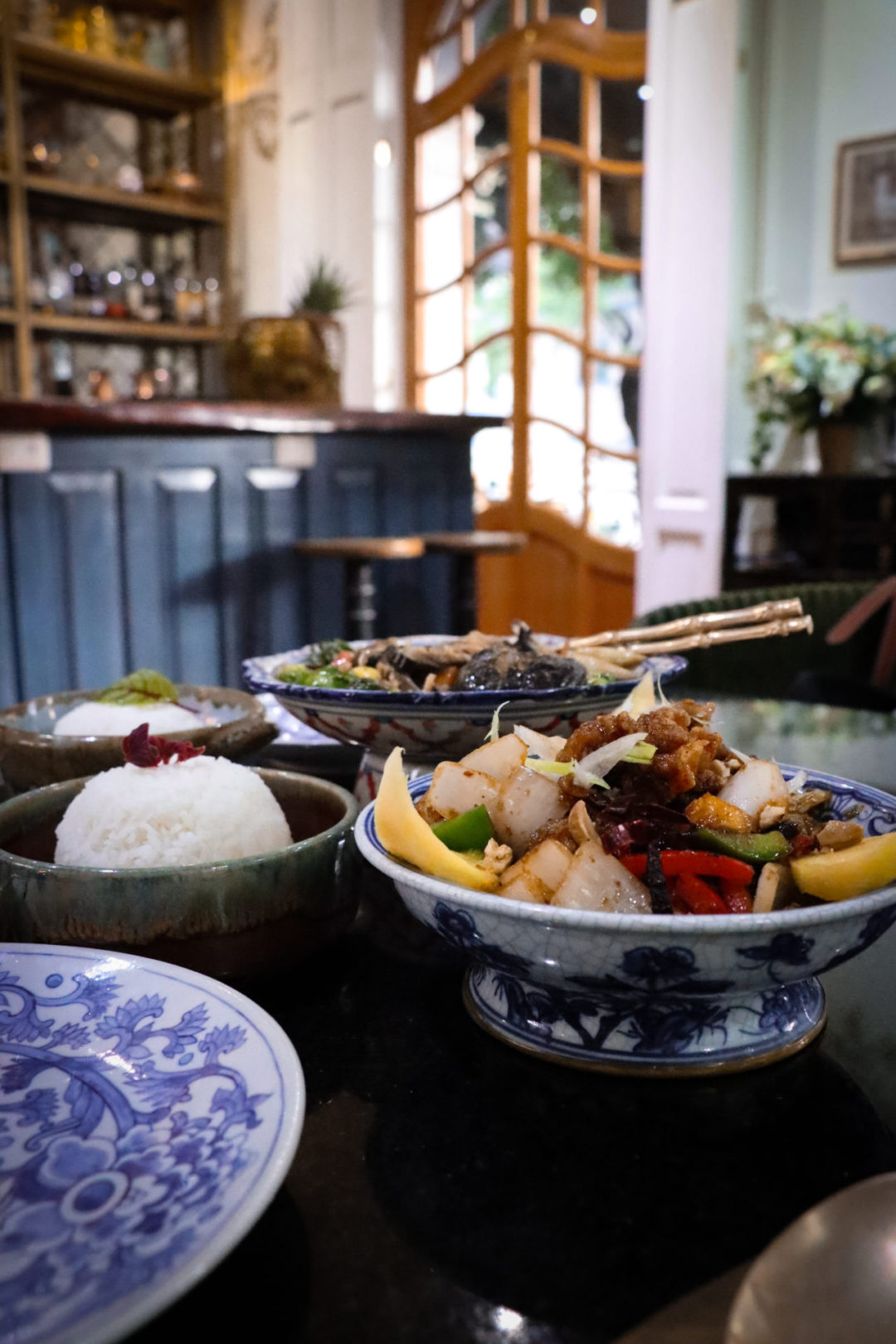Gai Pad Med Mamuang and See Sai Hai entrees on top a table with blue and white china at Galanga Thai Restaurant in Mexico City