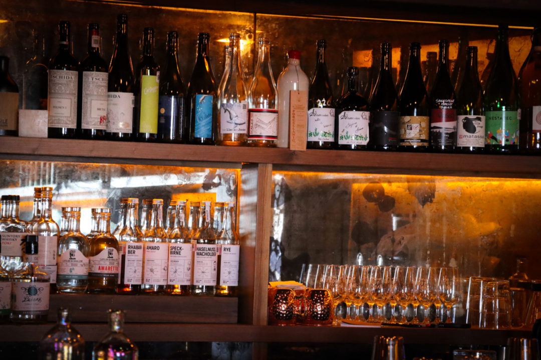 Multiple wine bottles and glass stemware adorn a shelf at Loup Wine Bar in Mexico City's Roma Norte neighborhood