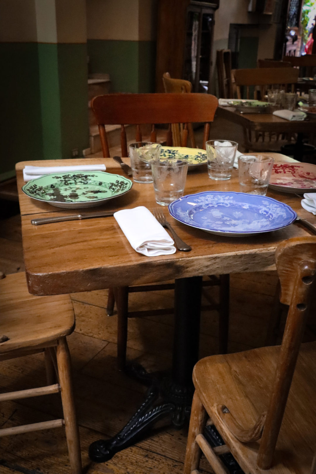 An few empty wooden table and chairs with colorful china inside Restaurante Rosetta, one of the best places to drink natural wine in Mexico City