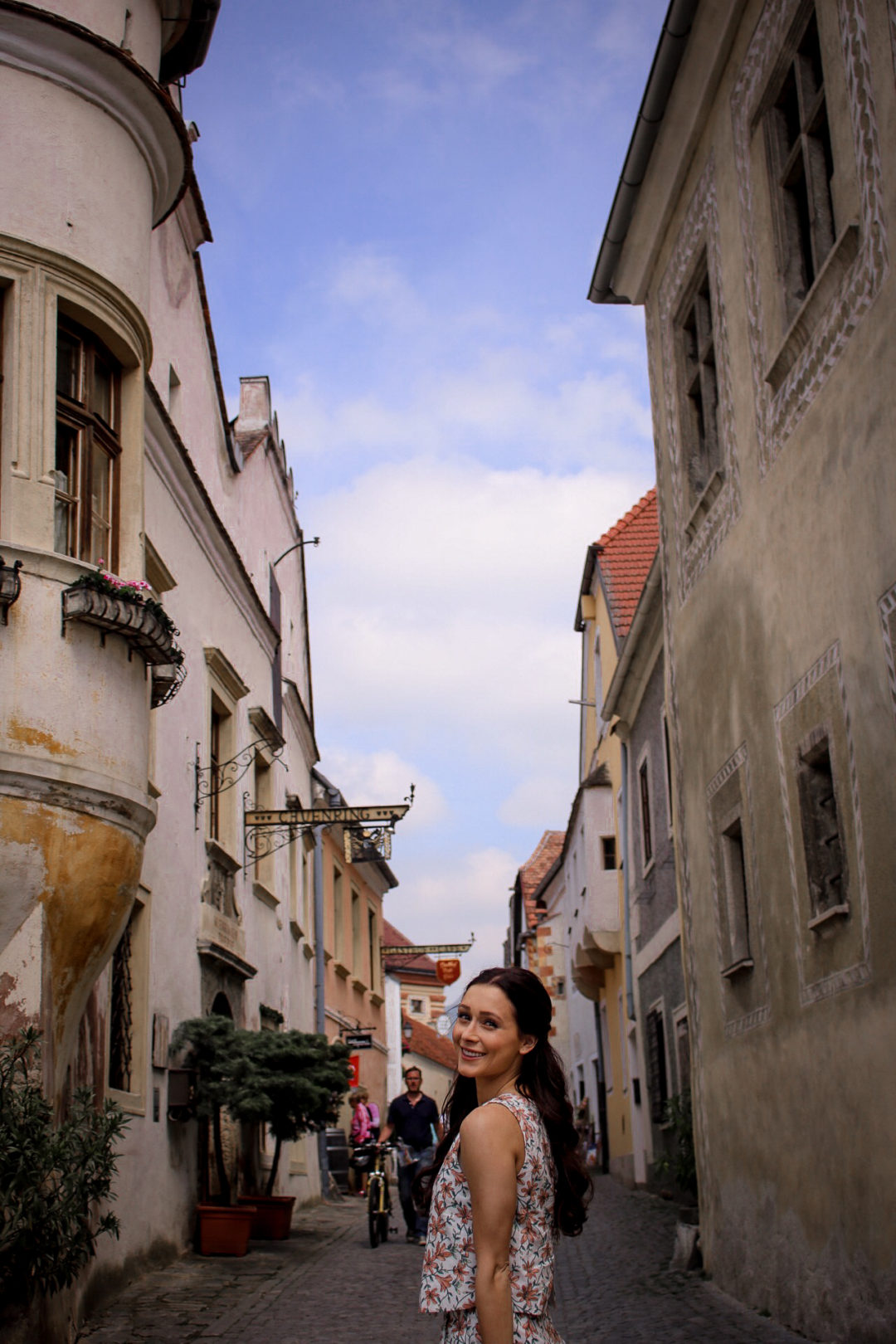 Travel Blogger Jordan Gassner smiling along a main cobblestone street in the Old Town of Durnstein, Austria
