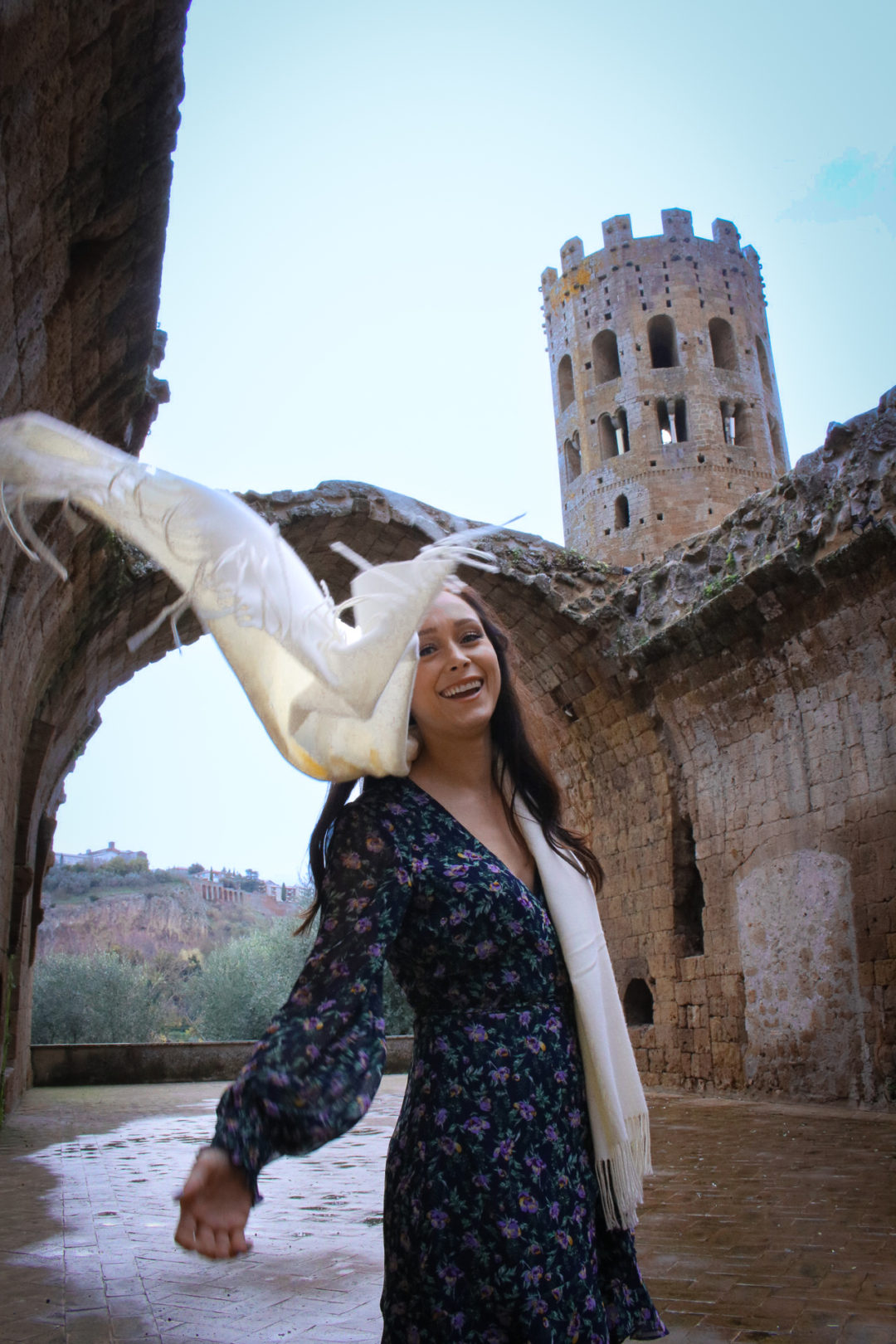 Travel Blogger Jordan Gassner flinging her cream scarf toward the camera in Orvieto, Italy