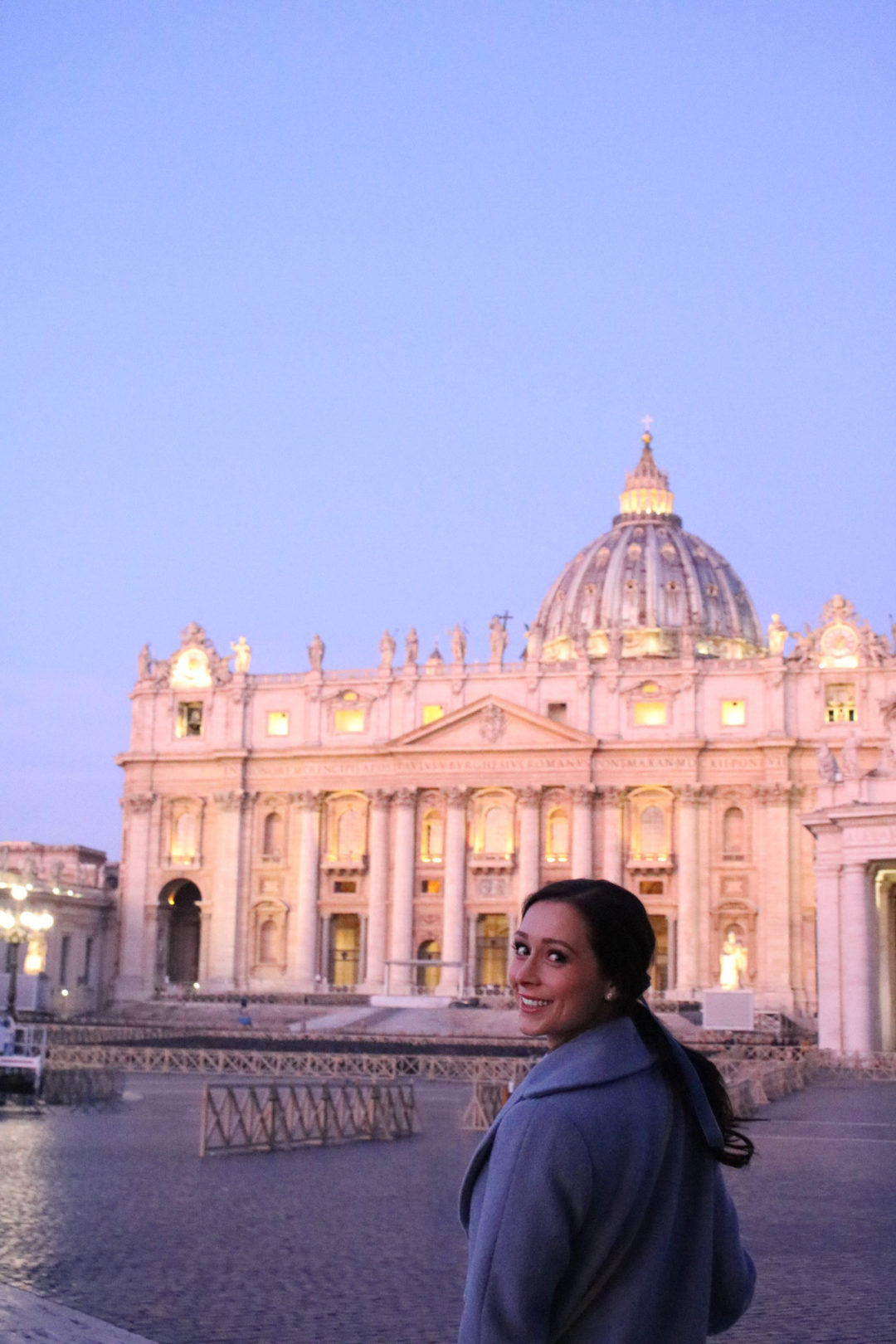 Travel Blogger Jordan Gassner smiling to a tripod camera setup while standing in front of Vatican City at twilight, before the tourists have arrived