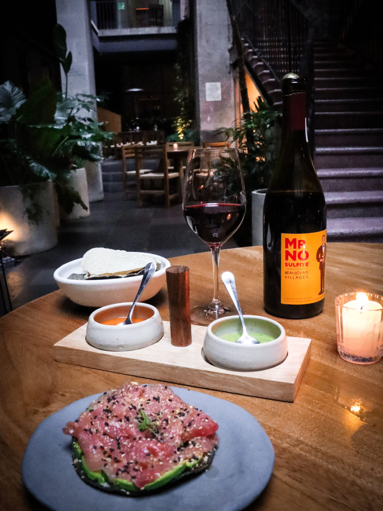 Tuna Tostada, Fried Tortillas with dip and a glass of red wine near a bottle of Mr. No Sulfite Beaujolais-Villages on a table at Caracol de Mar in CDMX