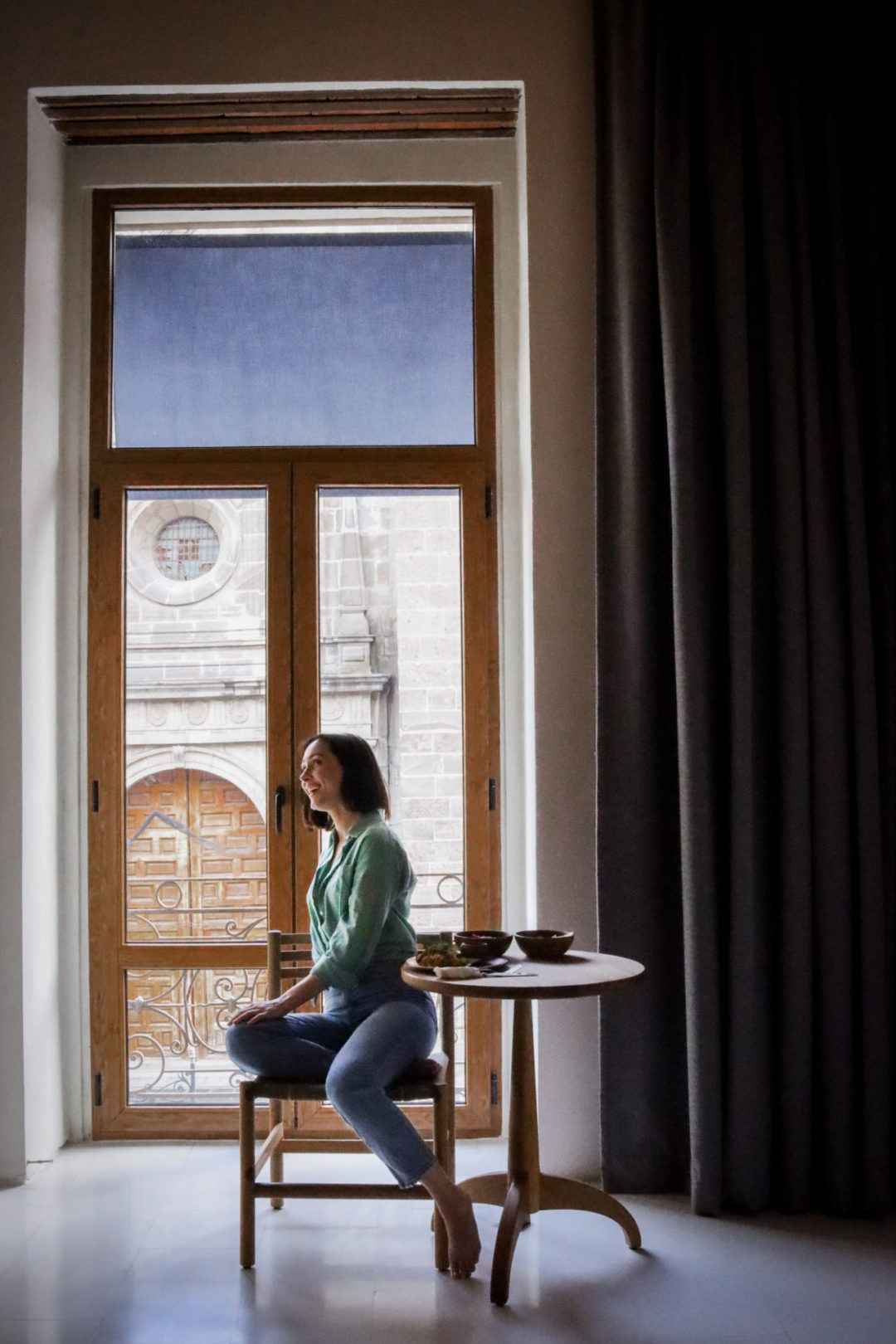 Travel Blogger Jordan Gassner sitting at a table in front of a balcony at the Círculo Mexicano Boutique hotel in Mexico City