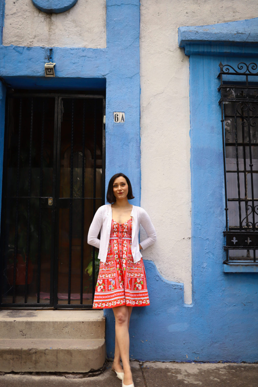 Travel Blogger Jordan Gassner smiling in front of a sky blue and white painted home in Coyoacán Mexico City