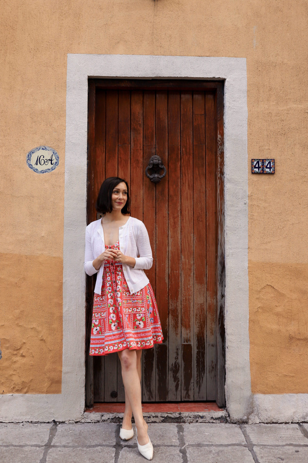 Travel Blogger Jordan Gassner leaning against a wooden doorway of a light orange painted home in Coyoacán Mexico City