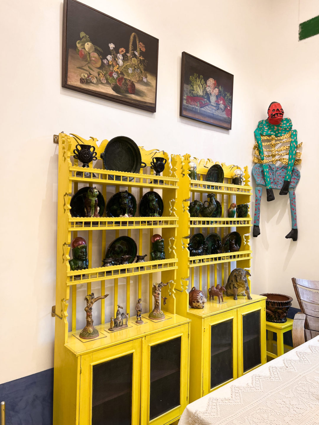 A bright yellow dresser displaying multiple sculptures and figurines inside the Frida Kahlo Museum in Mexico City